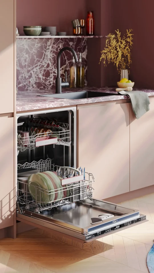Eine moderne Küche mit einem offenen Geschirrspüler, der mit Geschirr und Besteck gefüllt ist. Darüber befindet sich eine Marmorplatte mit Spüle. Im Hintergrund stehen mehrere Glasflaschen und eine Vase mit gelben Blumen.