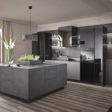 Moderne Küche mit dunkelgrauen Schränken und einer großen Kochinsel. Ein runder Bogenfenster lässt Licht in den Raum. Auf der Insel stehen eine Vase mit Blumen und ein Kräuterbehälter. Der Boden ist aus Holz.