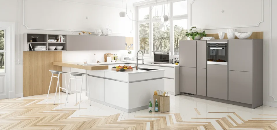 Helle, moderne Küche mit zwei Inseln, Holz- und weißen Akzenten. Geräte wie Herd und Backofen sind eingebaut. Dekorative Gegenstände stehen auf der Arbeitsfläche. Ein großes Fenster lässt Tageslicht herein.